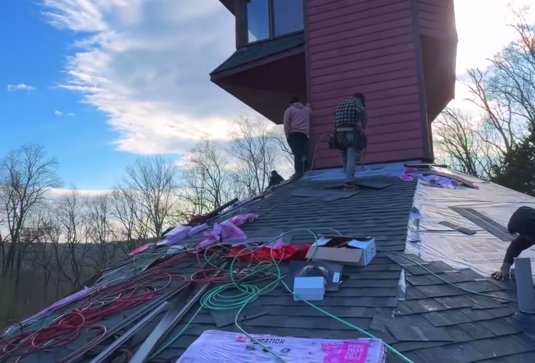 Roofers laying shingles at the base of the tower
